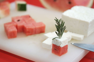 Close-up of watermelon and feta cheese cubes with rosemary on cutting board