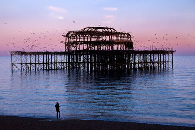 Silhouette man on beach against sky during sunset