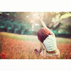 Rear view of woman sitting on field