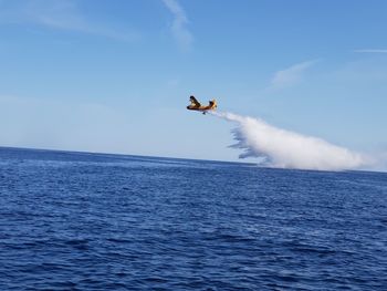 Man flying over sea against blue sky