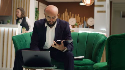 Side view of young man using laptop at home