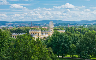 Trees and buildings in city against sky