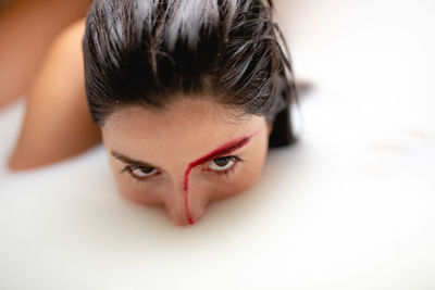 Close-up portrait of young woman taking milk bath