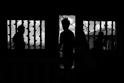 Silhouette man standing against window