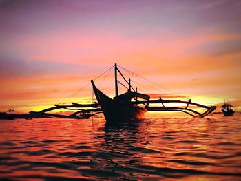 Silhouette boats in sea against sky during sunset