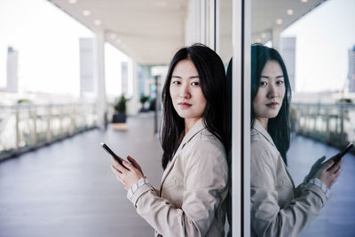 Confident beautiful chinese business woman using mobile phone in city. technology
