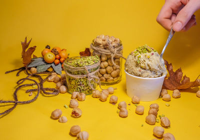 Cropped hand of person with food on yellow background