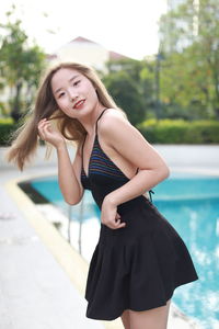 Portrait of young woman standing against railing