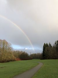 Scenic view of rainbow over field against sky