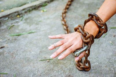 Close-up of hand tied with metal chain