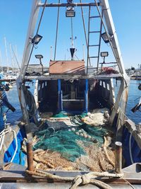 Fishing boats moored at harbor against sky