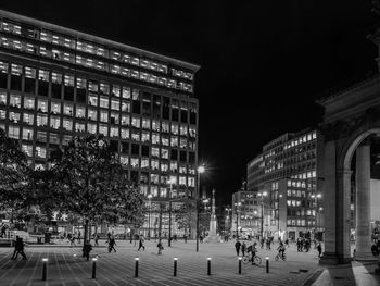 People walking on illuminated street at night