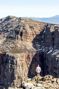 Rear view of man on rock against sky