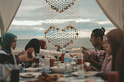 Group of people sitting dinner with sea view background