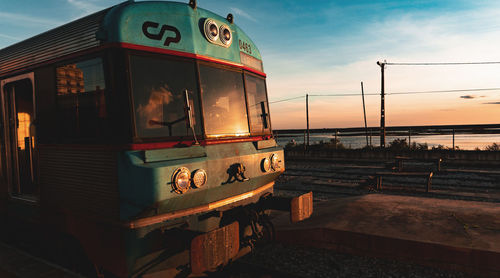 Train on railroad tracks against sky during sunset