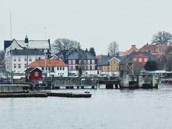 Buildings by sea against clear sky