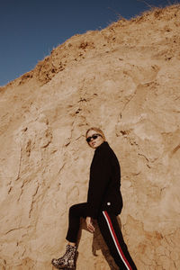 Full length portrait of woman standing against mountain and sky