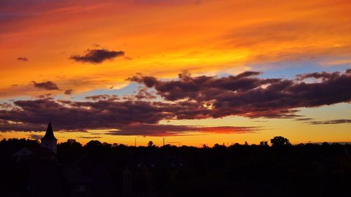 Silhouette trees against dramatic sky during sunset