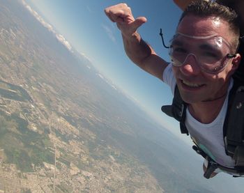 Portrait of young man skydiving over landscape