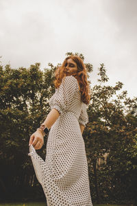 Midsection of woman standing by tree against plants
