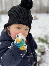 Cute boy eating food outdoors during winter