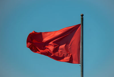 Low angle view of flag against blue sky