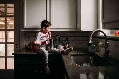Young boy sitting on counter drinking frothed milk in the morning