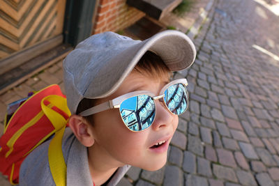 A little boy looks with reflecting sunglasses around