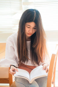 Beautiful young woman sitting on book