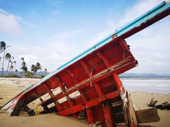 View of abandoned boat on beach against sky