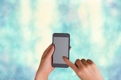 Midsection of man using mobile phone against blue sky