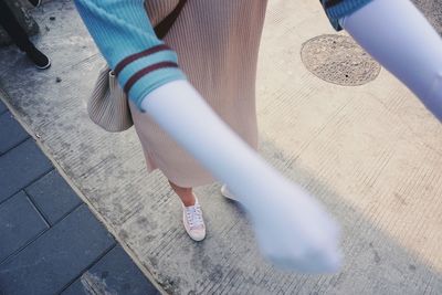 Low section of woman wearing gloves standing on footpath