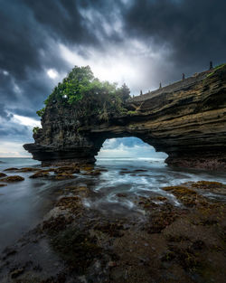 Rock formation on sea shore against sky