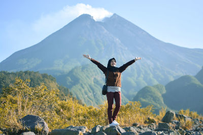 Rear view of man standing on mountain against sky