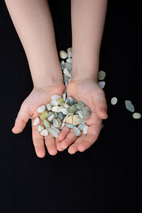 High angle view of hands holding ice cream over black background