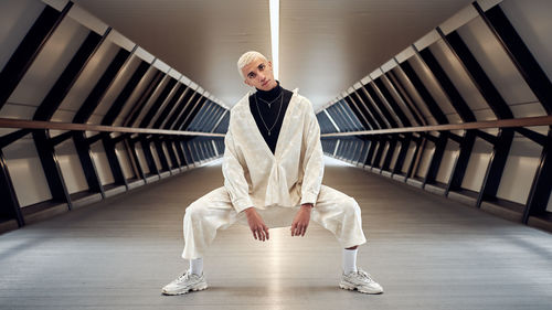 Full length portrait of young man standing in corridor