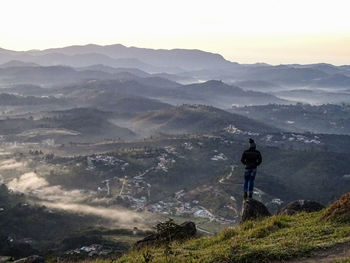 Rear view of man standing on mountain against sky