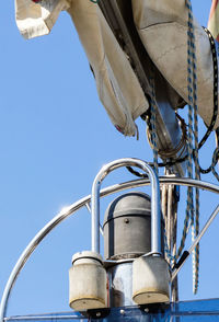 Low angle view of machinery on boat against blue sky