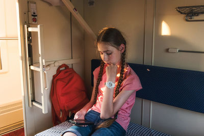 Close-up of girl looking down while sitting in illuminated room