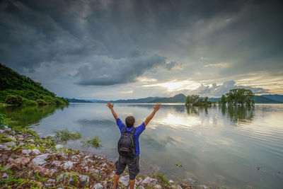 People by lake against sky