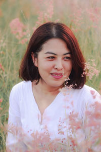 Portrait of smiling young woman standing against plants