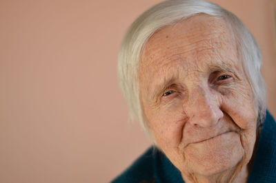 Close up portrait of a smiling senior 90 years woman. studio shot over beige background.