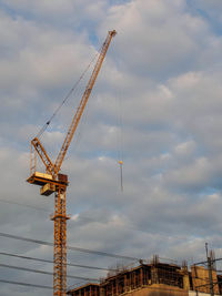 Low angle view of cranes against sky