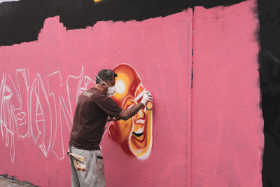 Rear view of man standing by pink wall