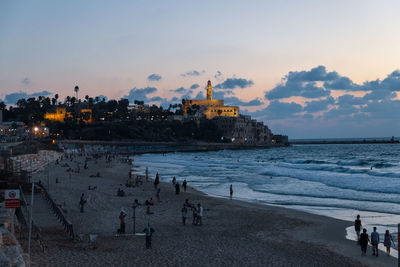 People on beach against sky during sunset