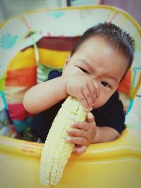 Close-up of baby with corn in stroller