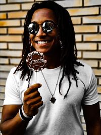 Portrait of smiling young man wearing sunglasses holding sweet food