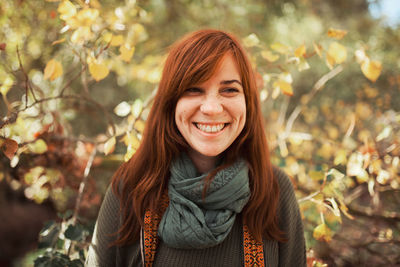 Close-up of smiling young woman looking away against plants