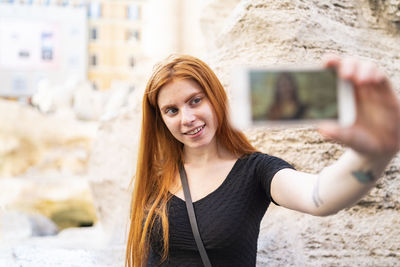 Young female traveler taking selfie in city