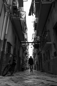 Rear view of man walking on street amidst buildings